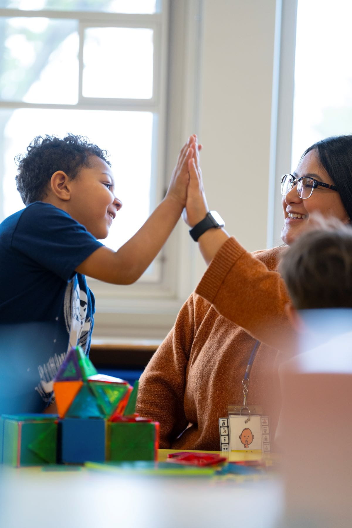 A teacher and a student high fiving in a classroom