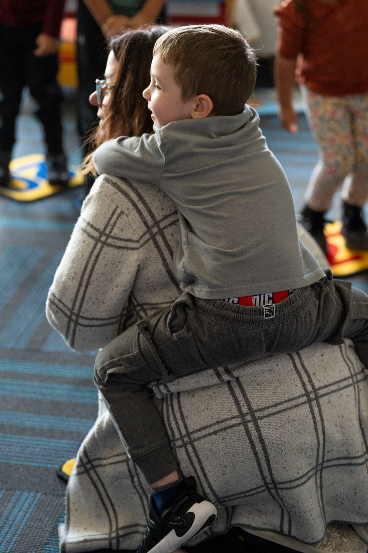 A student hugging a teacher while they are seated on the floor