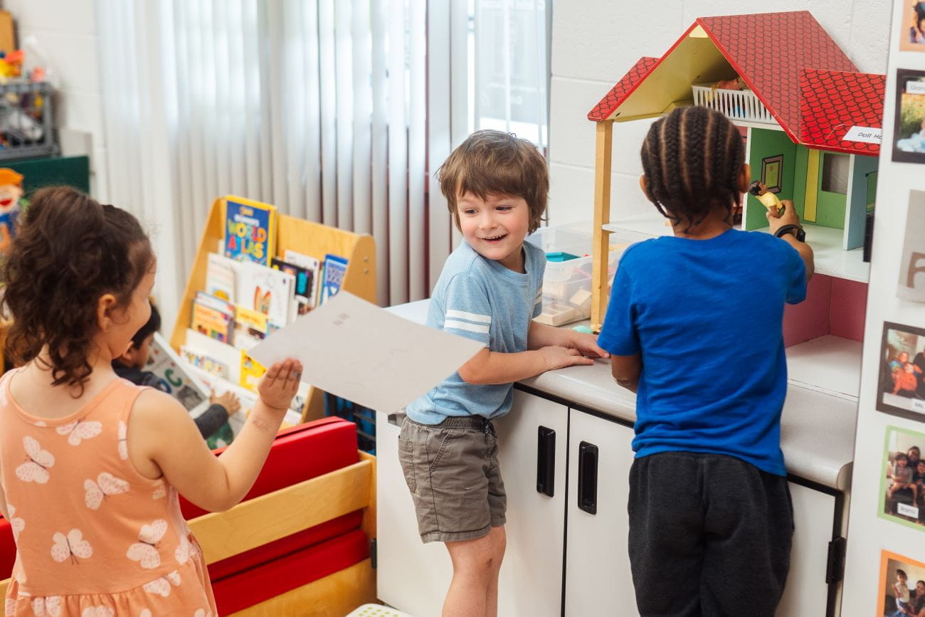 Two young children playing with a toy kitchen set in a preschool classroom