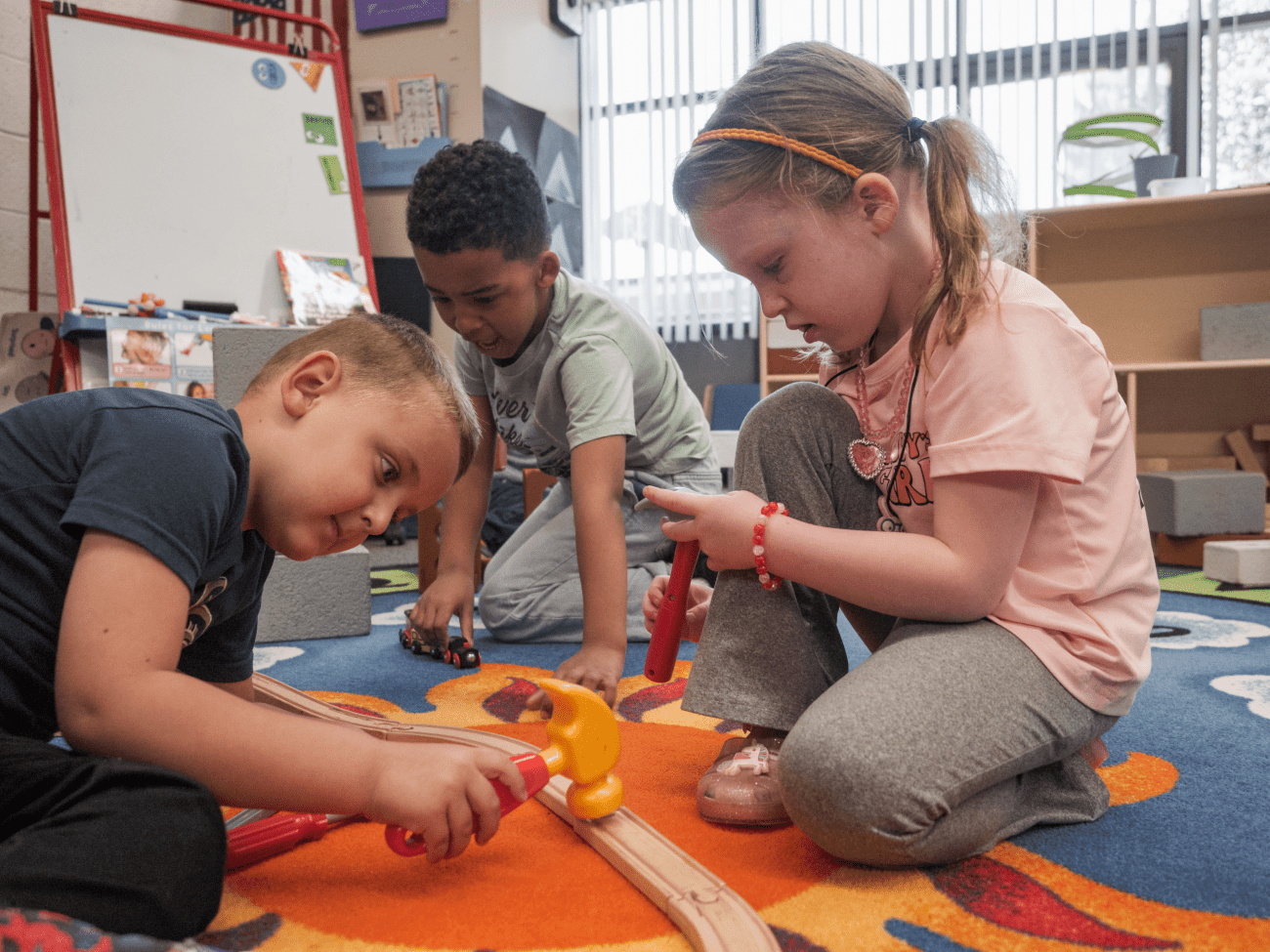 Young children playing together on a rug in a preschool classroom