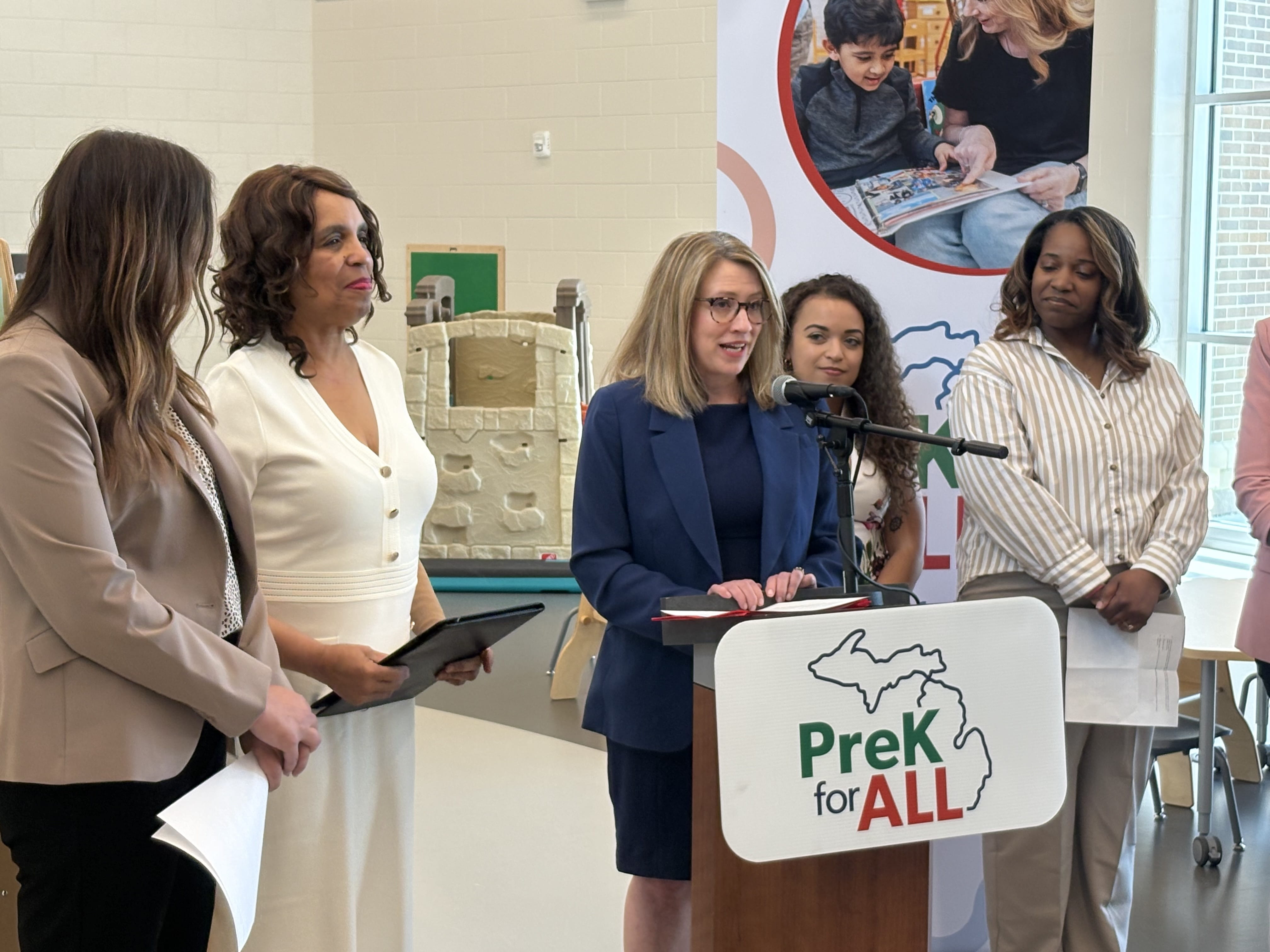 Emily Laidlaw stands at a podium, speaking at a PreK for All press event