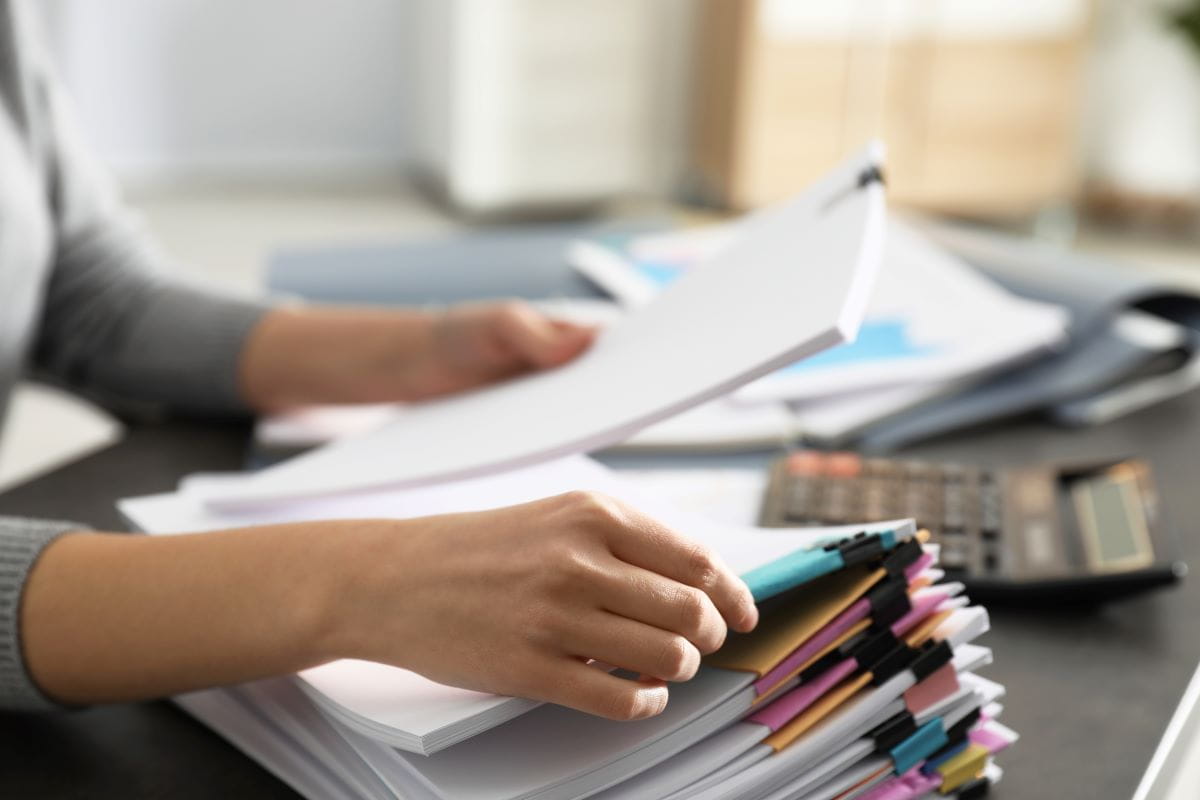 Woman sitting at a desk looking through a stack of papers