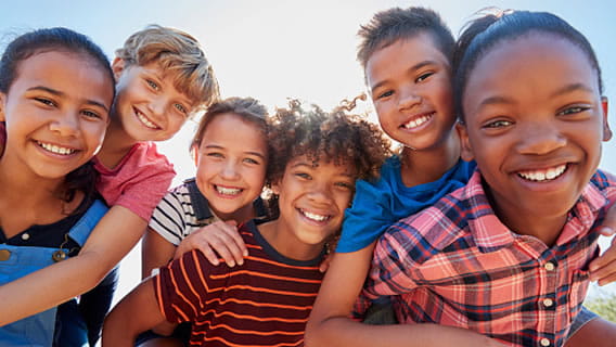 six middle school aged students outside smiling into the camera