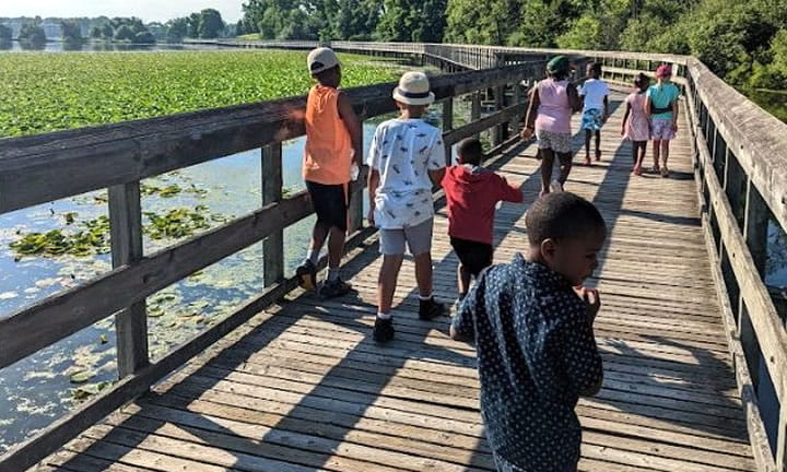 children walking on a bridge across a lake