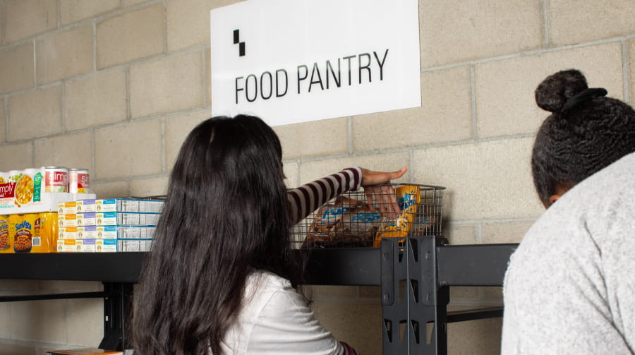 Two people looking at food at a food pantry.