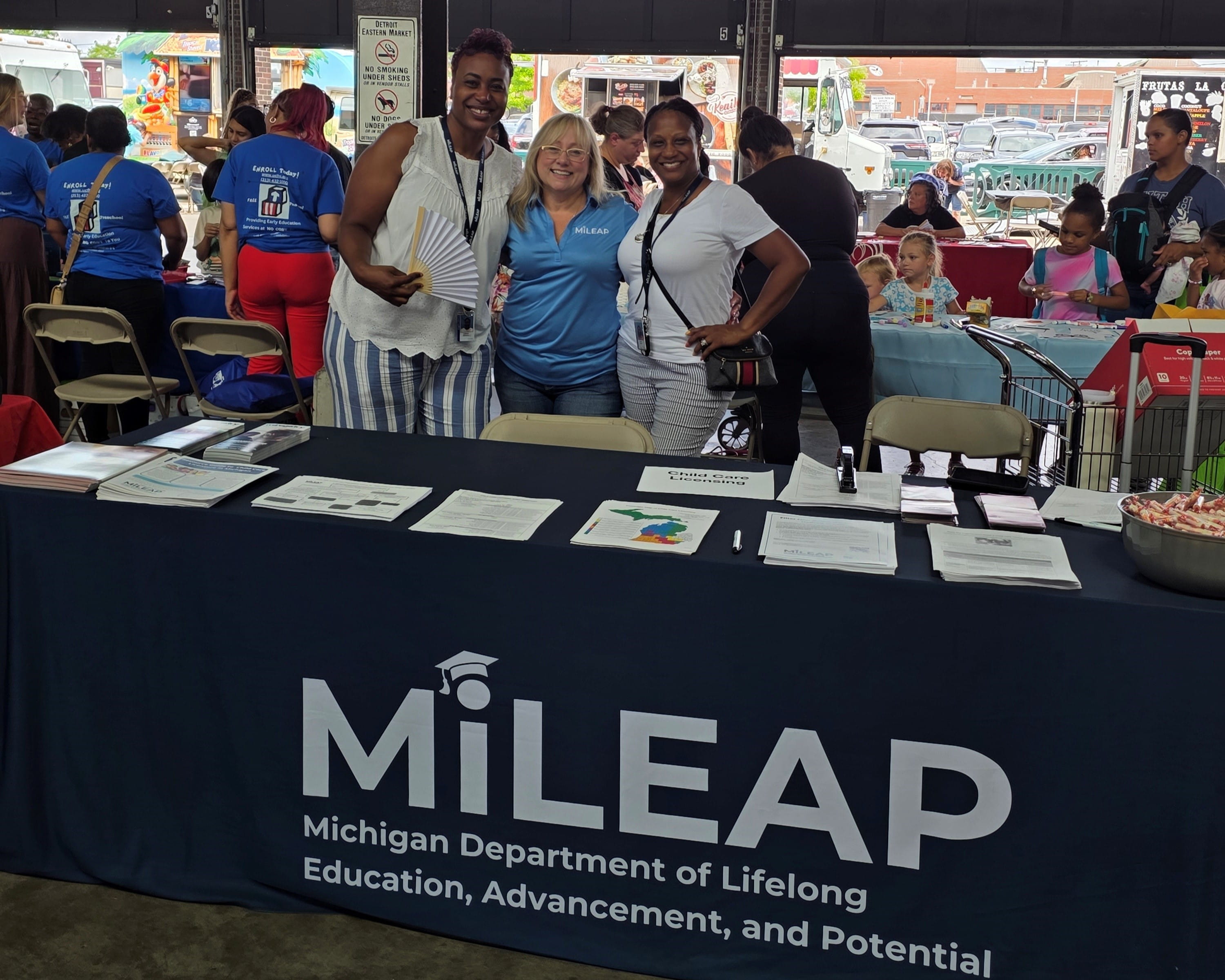 MiLEAP staff stand behind table at an event