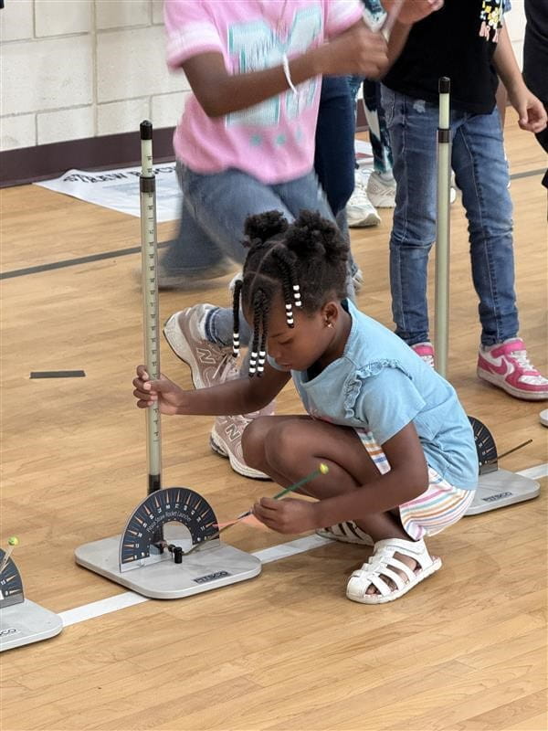 A student doing an activity on the floor of a gym