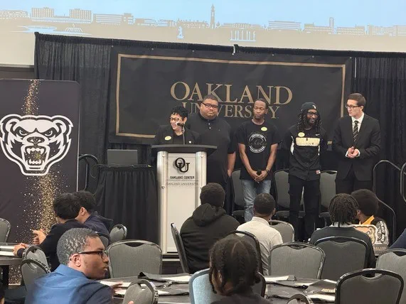 Teresa Rodges, senior director of Community Service and Pre-College Programs at Oakland University introduces student and alumni panelists Marcus Johnson, Jayson Miller, James Mitchell and Adam Schmitz for a discussion on student experiences and advice