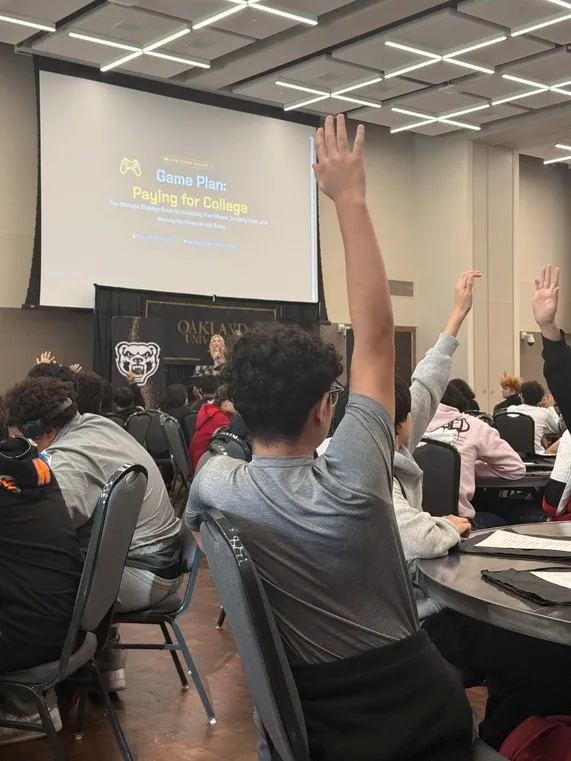 Students raise their hands to participate in an engaging college budget exercise.