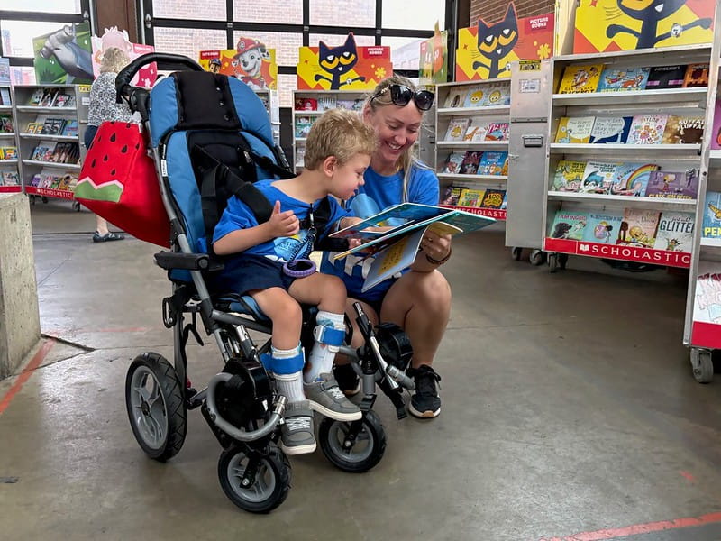 Young child looks at a book with his guardian at book fair event