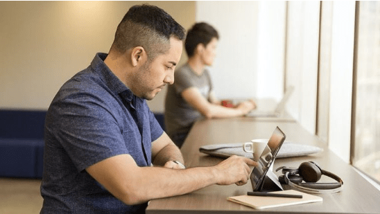 Adult standing and working on a laptop on a table