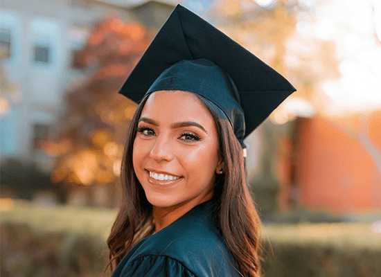A graduate standing outside.