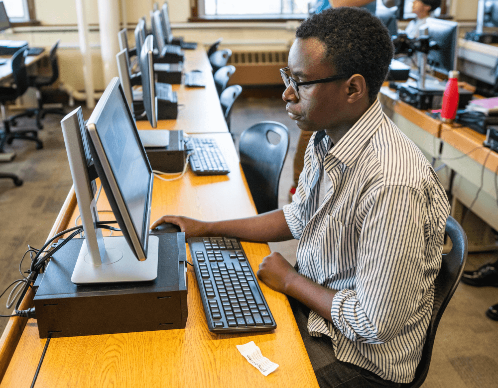 Someone sitting at a computer in a computer lab.