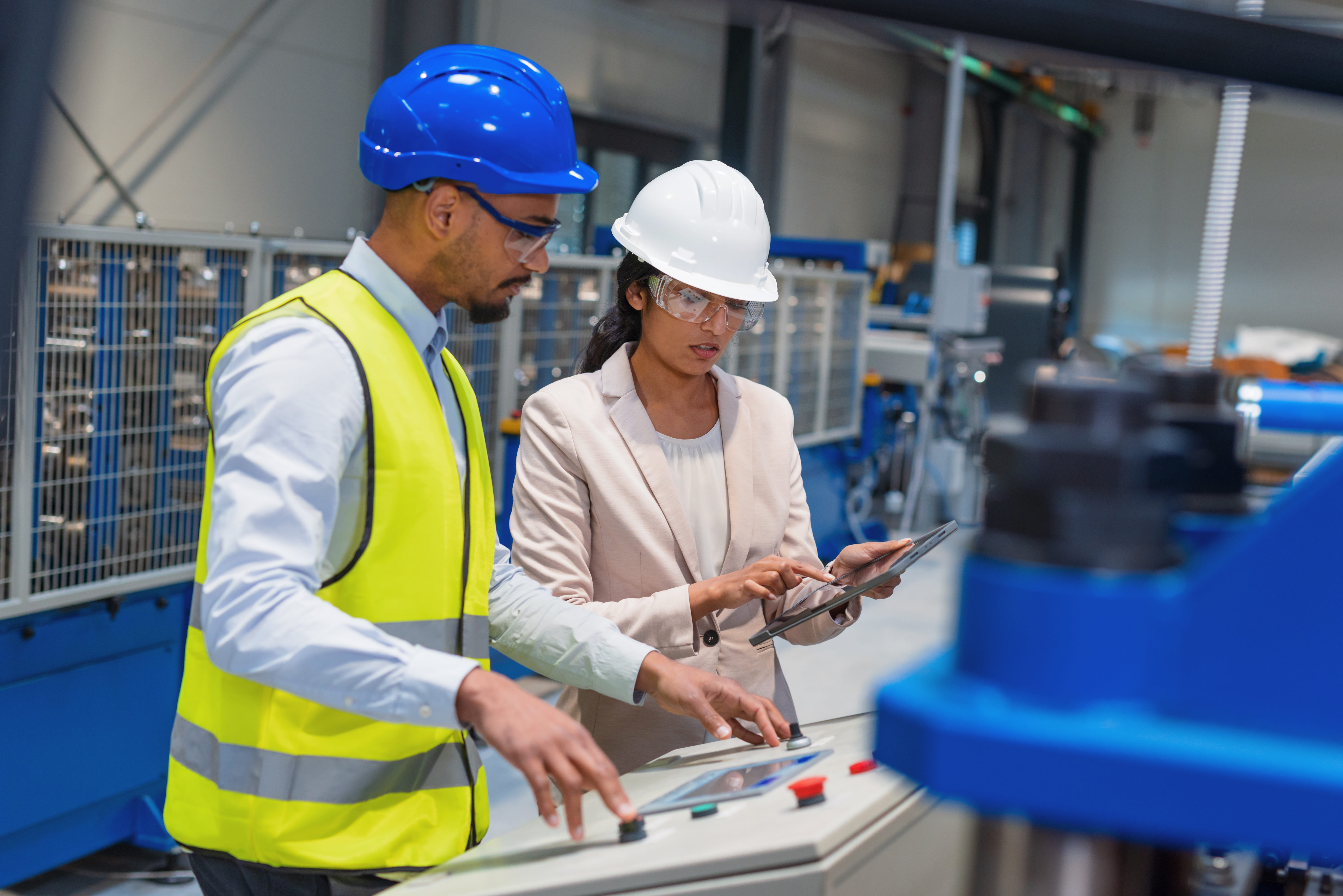 two people with hardhats on working with mechanical equipment