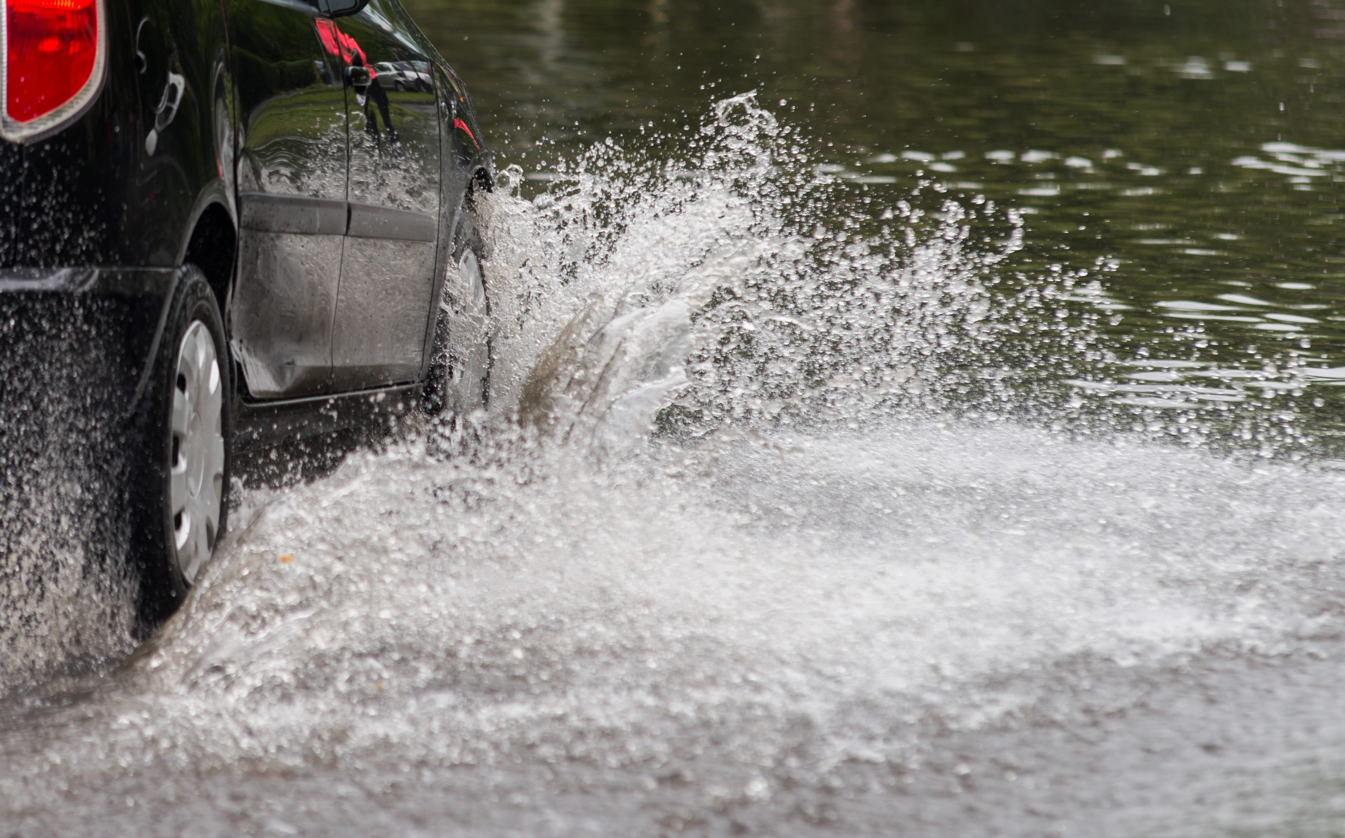 A car driving into what a large puddle of water