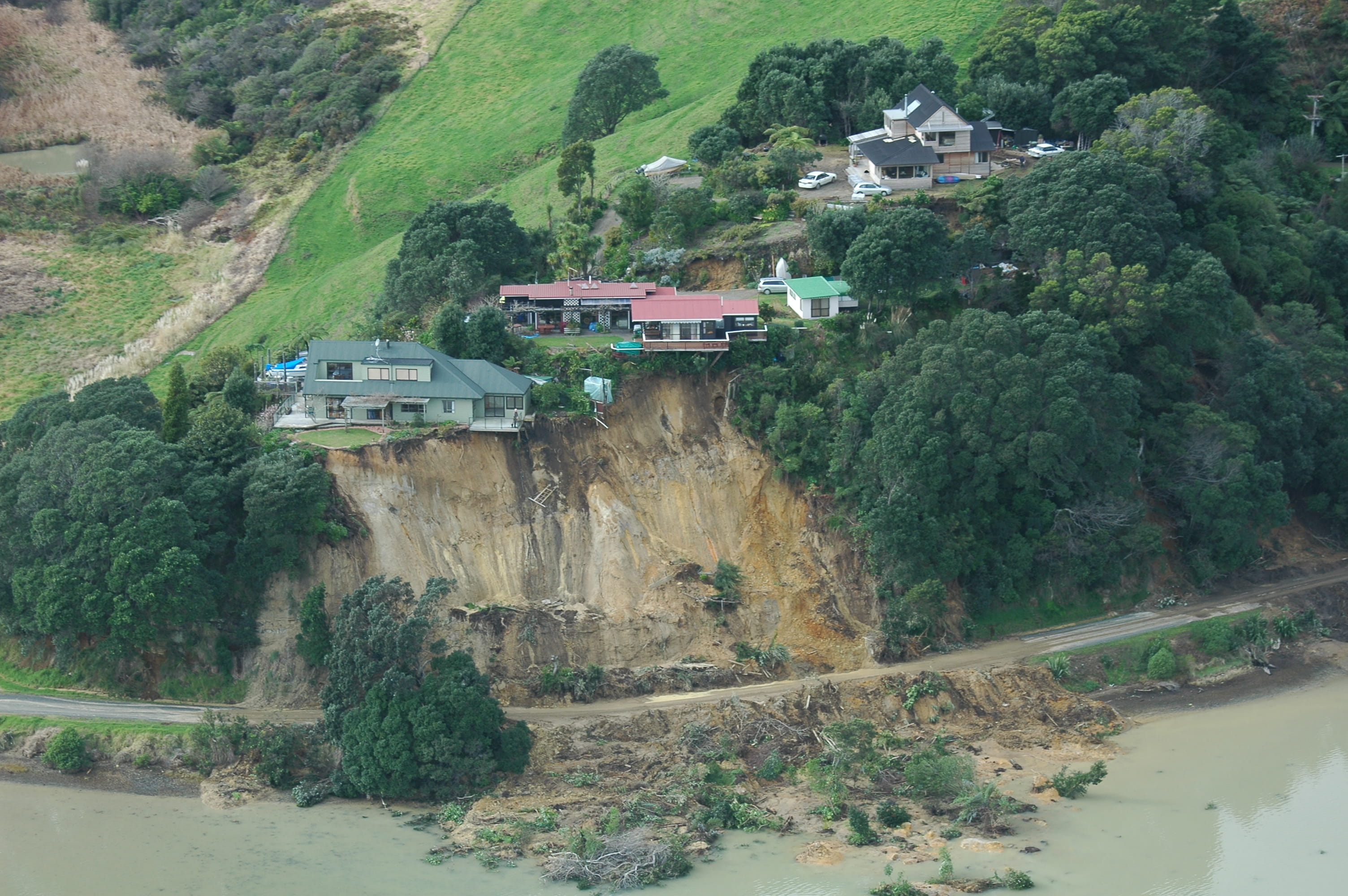 An aerial view of houses on a cliff that has experienced a landslide. 