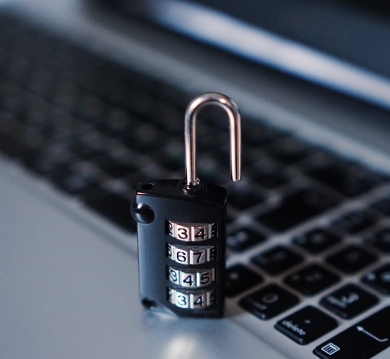 Combination lock in focus in foreground; laptop out-of-focus in background