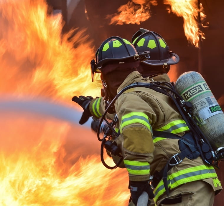 Two firefighters holding back a blaze