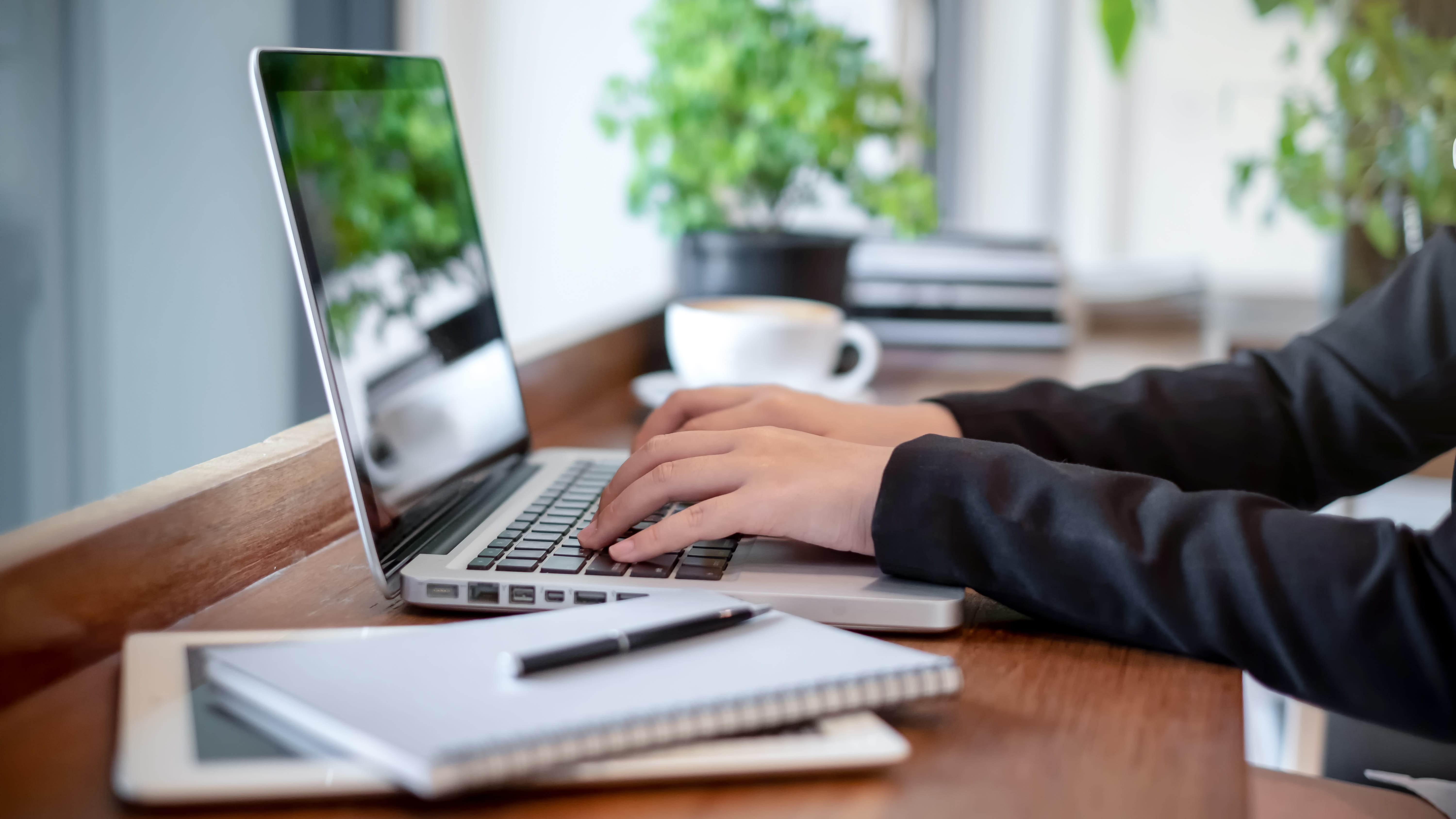 laptop on desk with a person typing