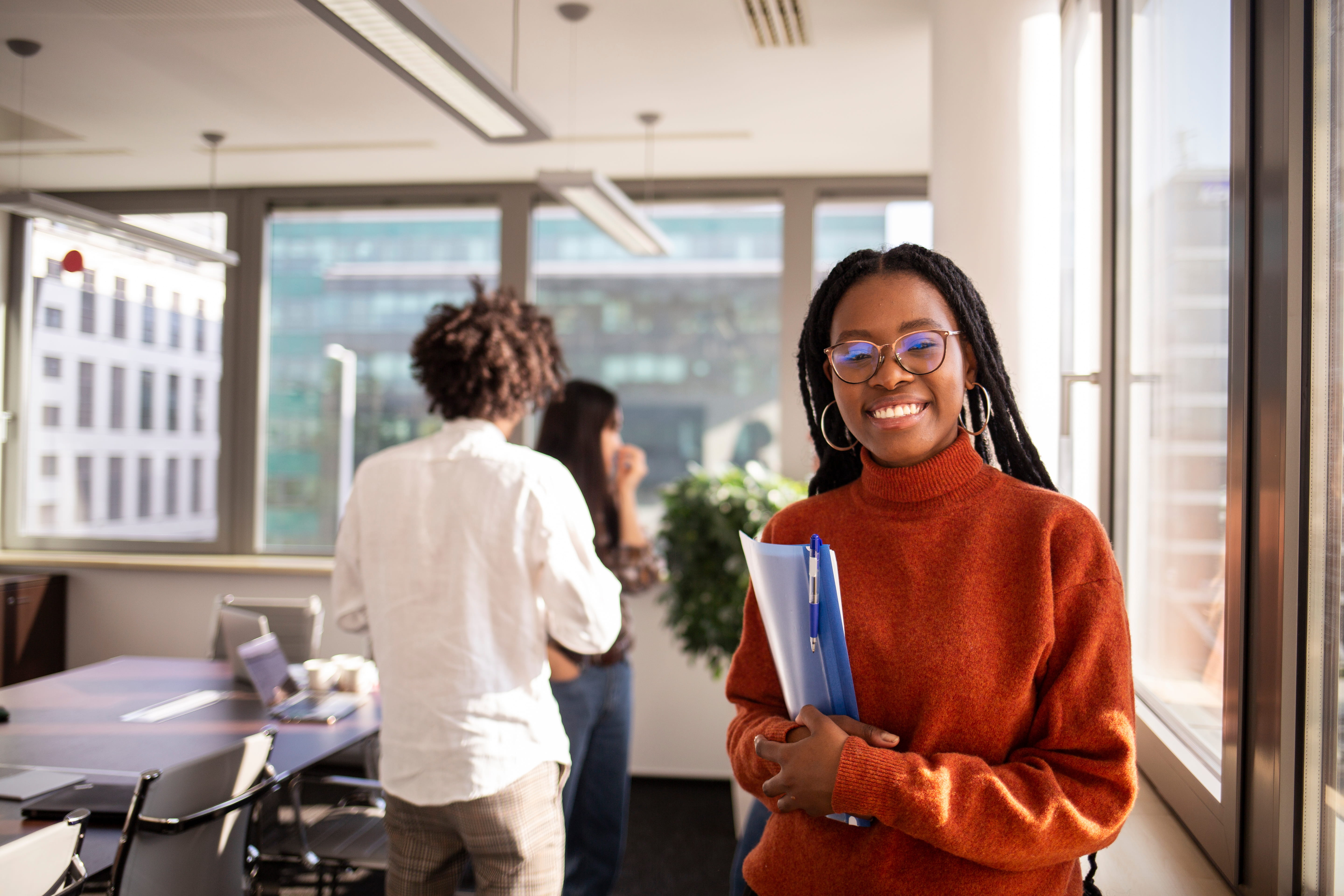Person smiling holding books in an office environment