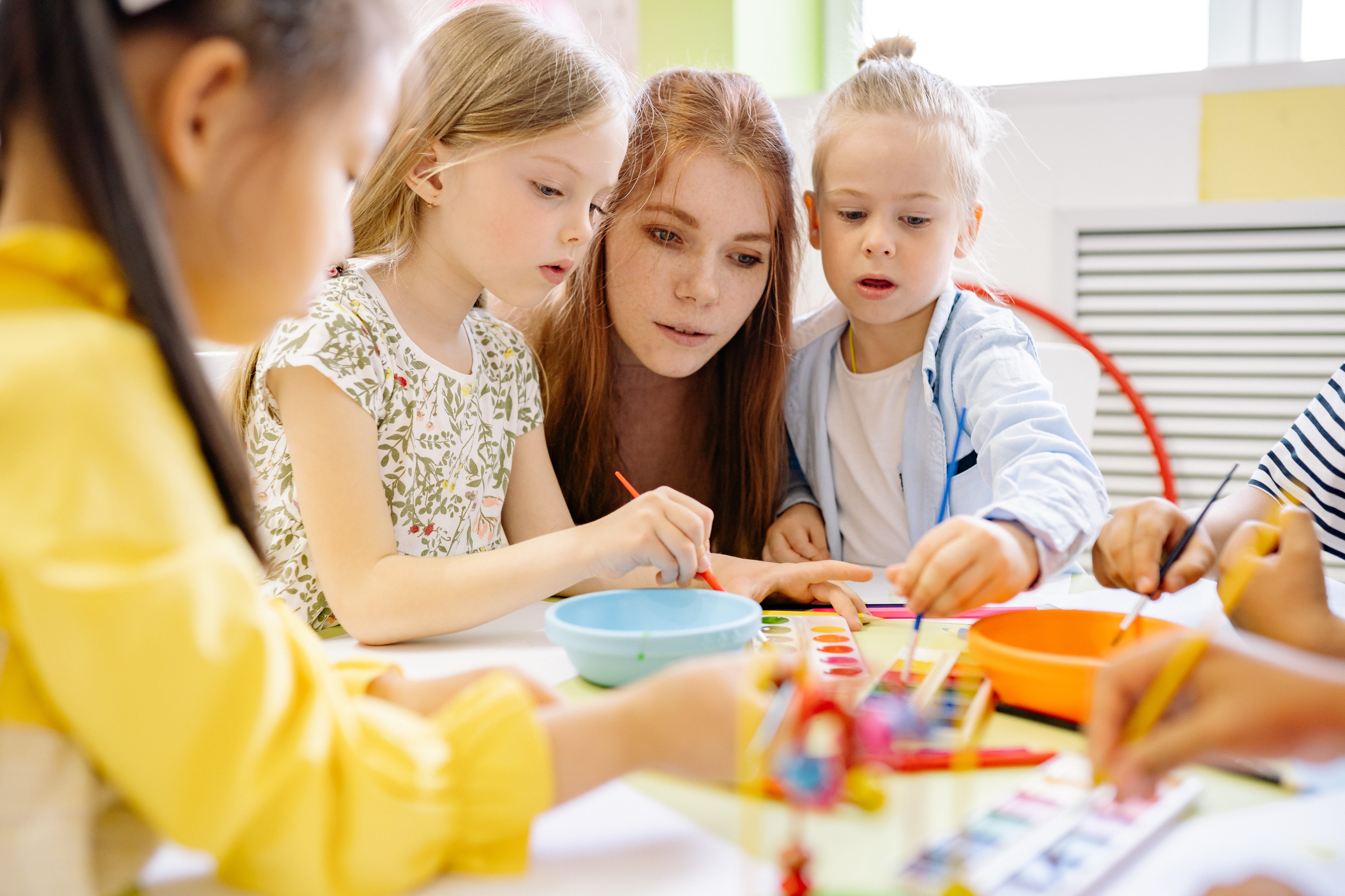 A teacher sitting with students at a table.