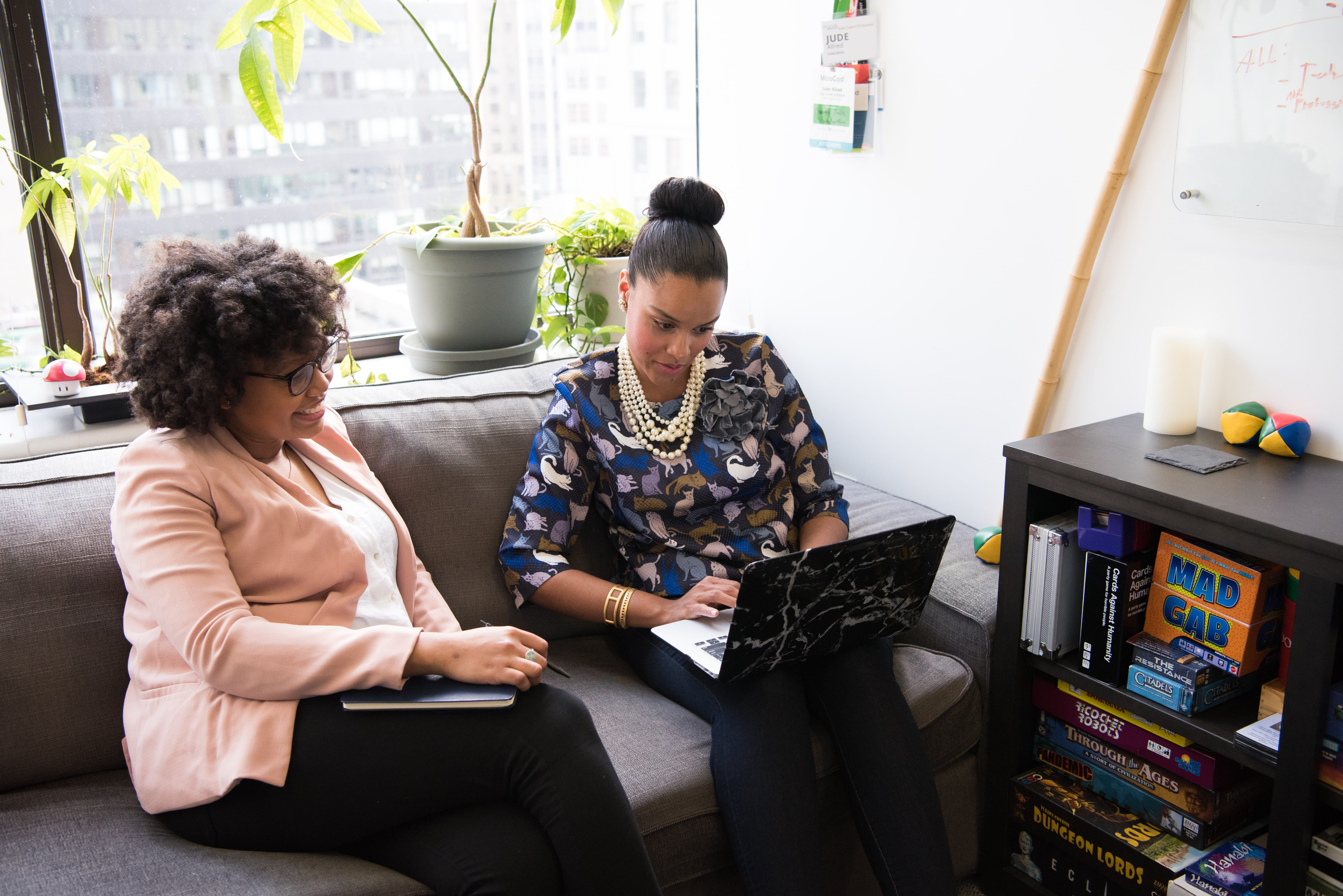 Two people sitting on a couch working on a computer.