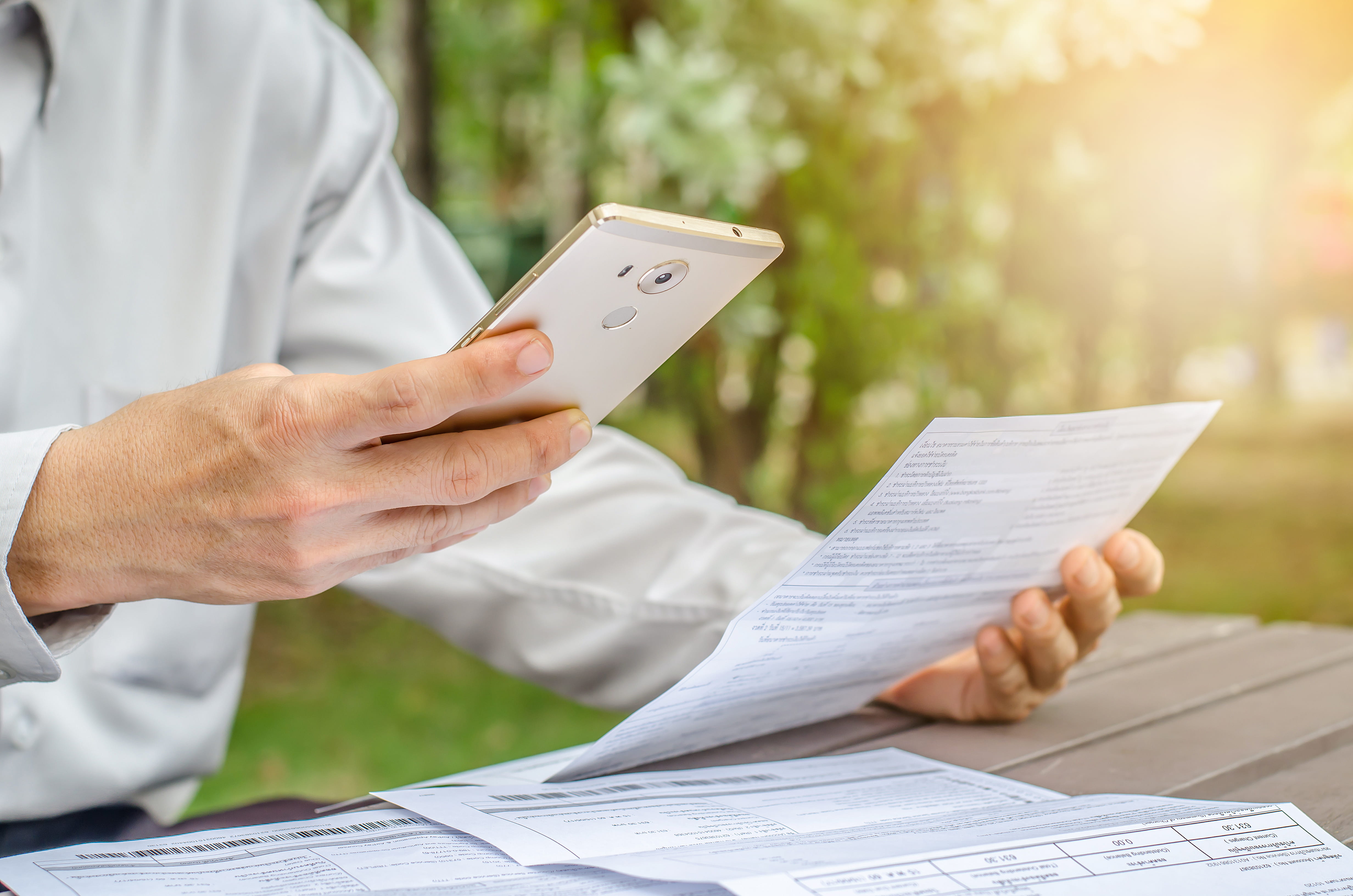 Businessman with bills and smart phone at the table.