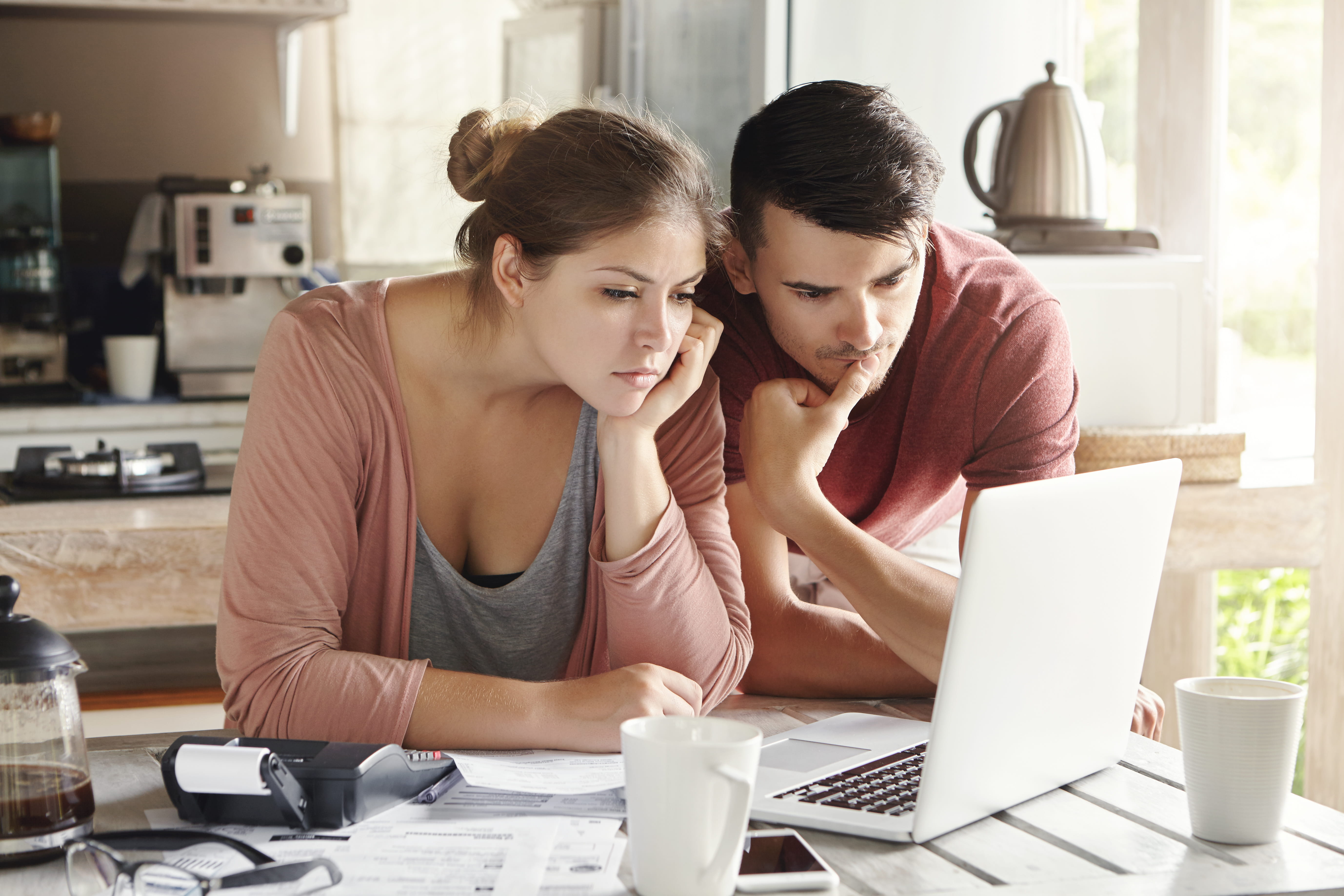 Young man and woman working together on laptop, paying utility bills via internet