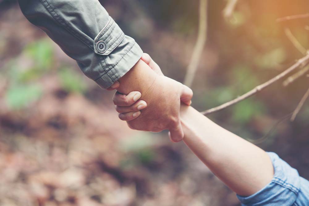 An arm clasping another arm, helping to lift them up