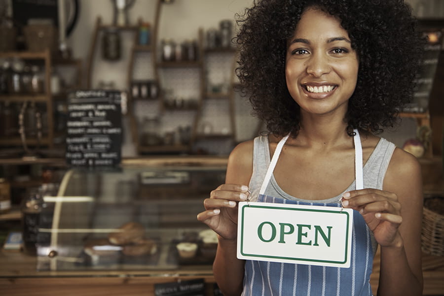 Woman holding an open sign at a bakery