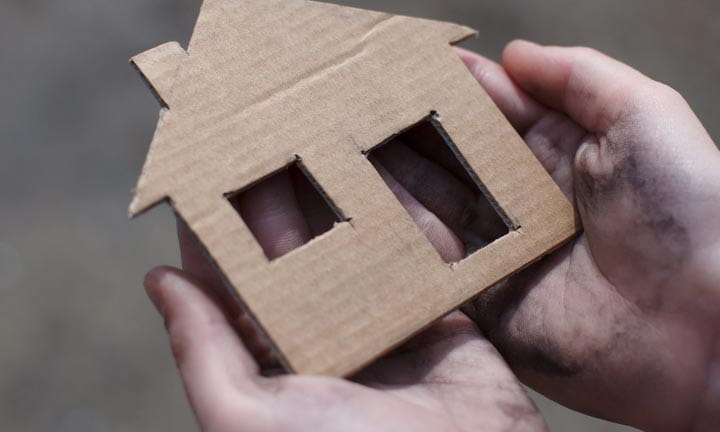 hands holding cardboard cut-out of a house