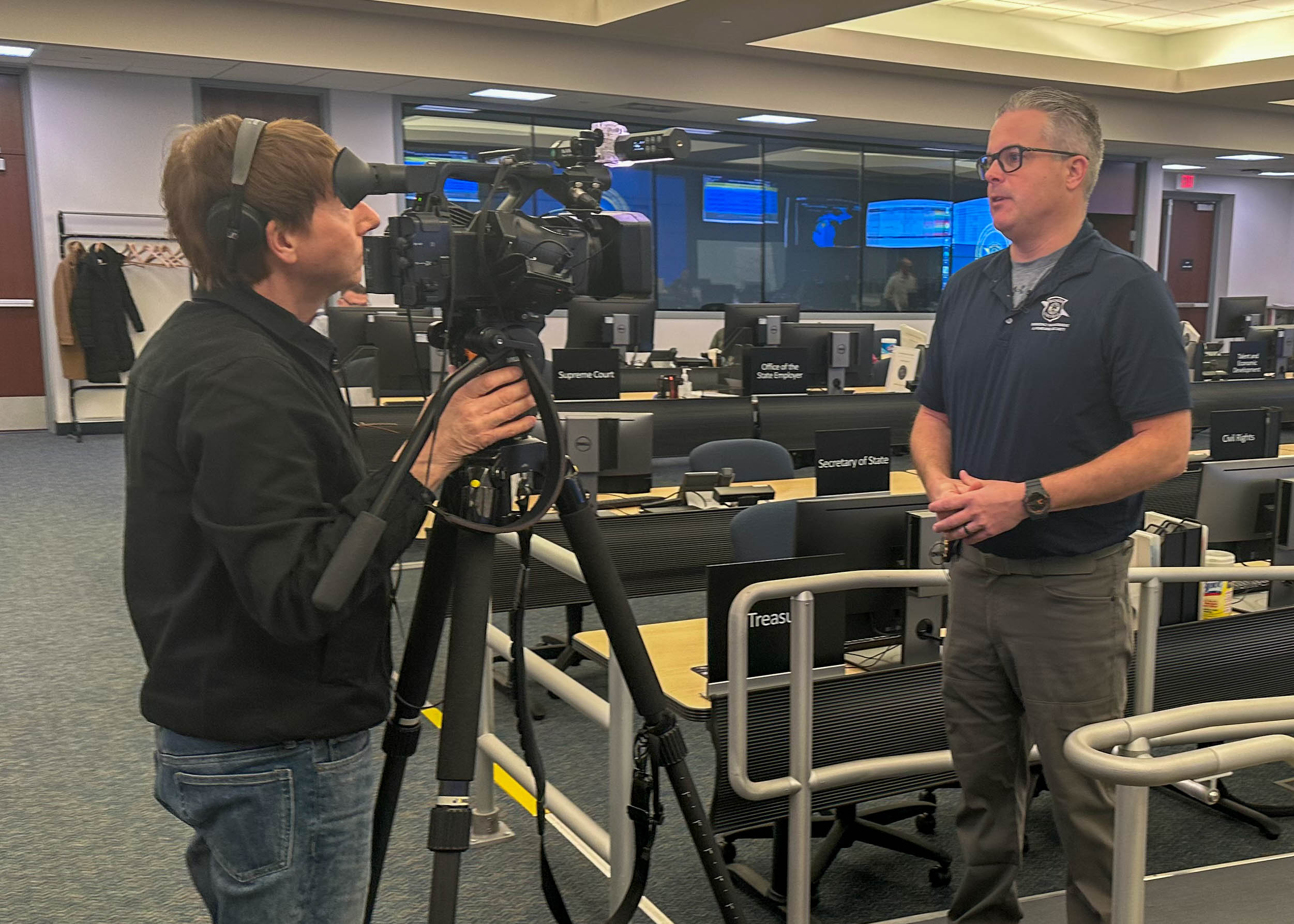 A camera person interviewing another person in the State Emergency Operations Center.