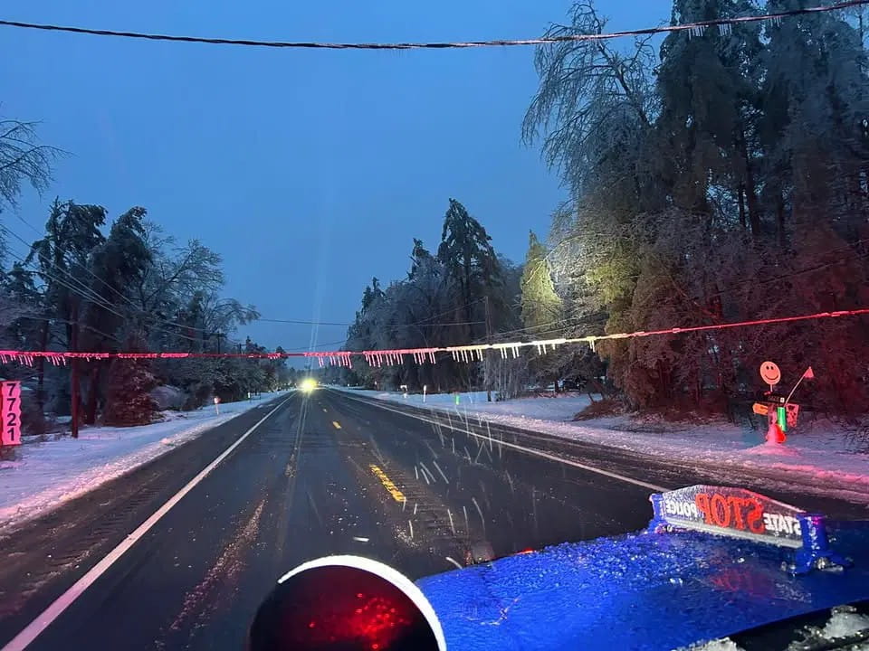 Powerlines that are hanging very low across a road due to heavy snow and ice. 