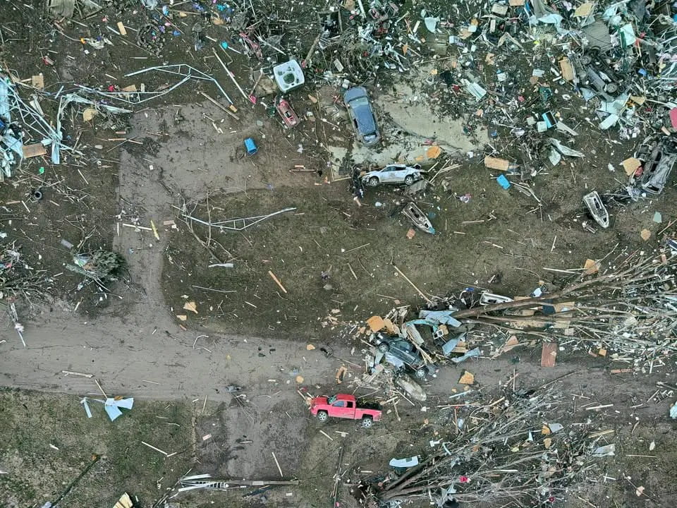 An aerial view of tipped cars and debris from damaged buildings caused by a tornado.