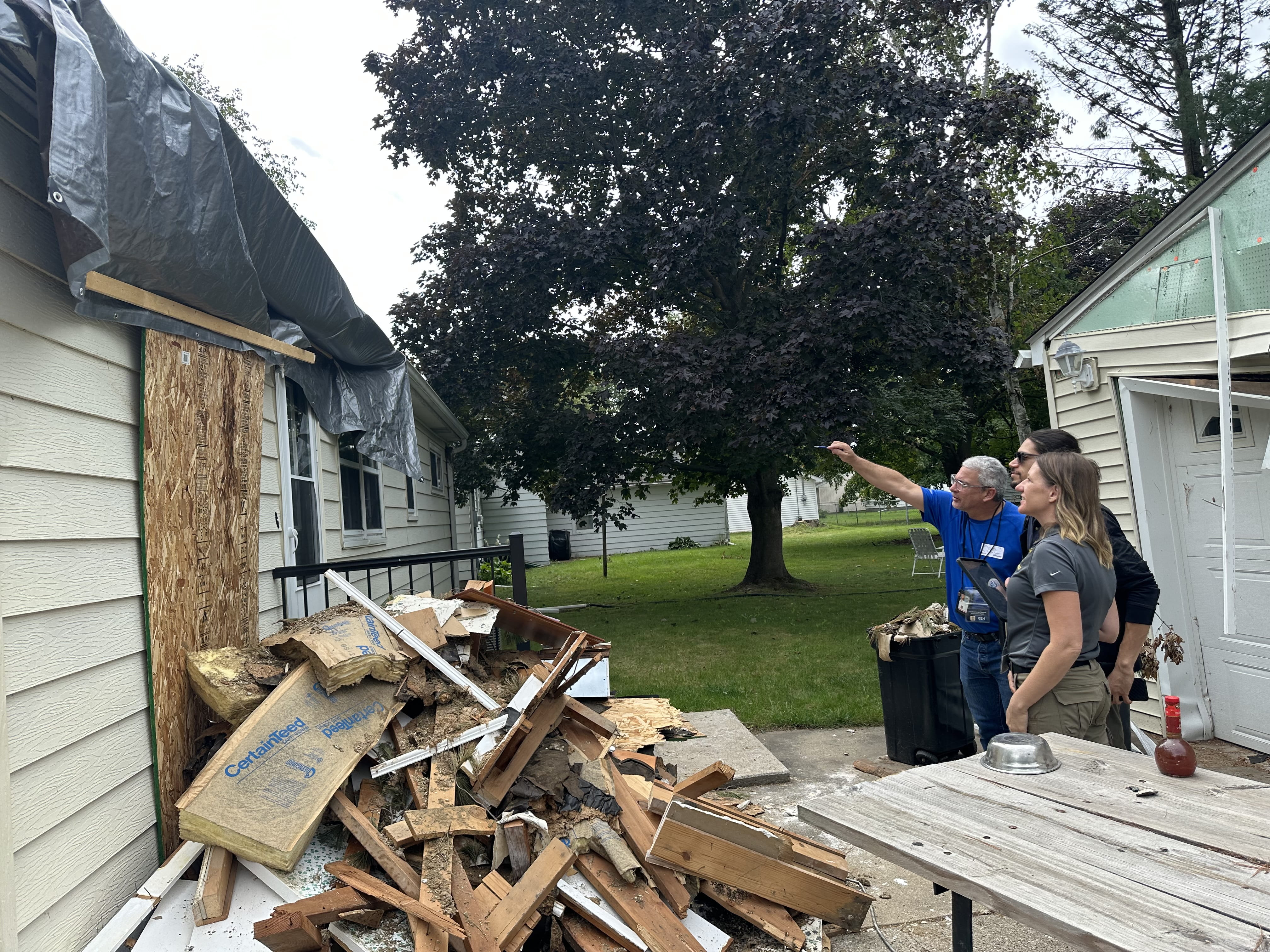 People assessing a damaged house