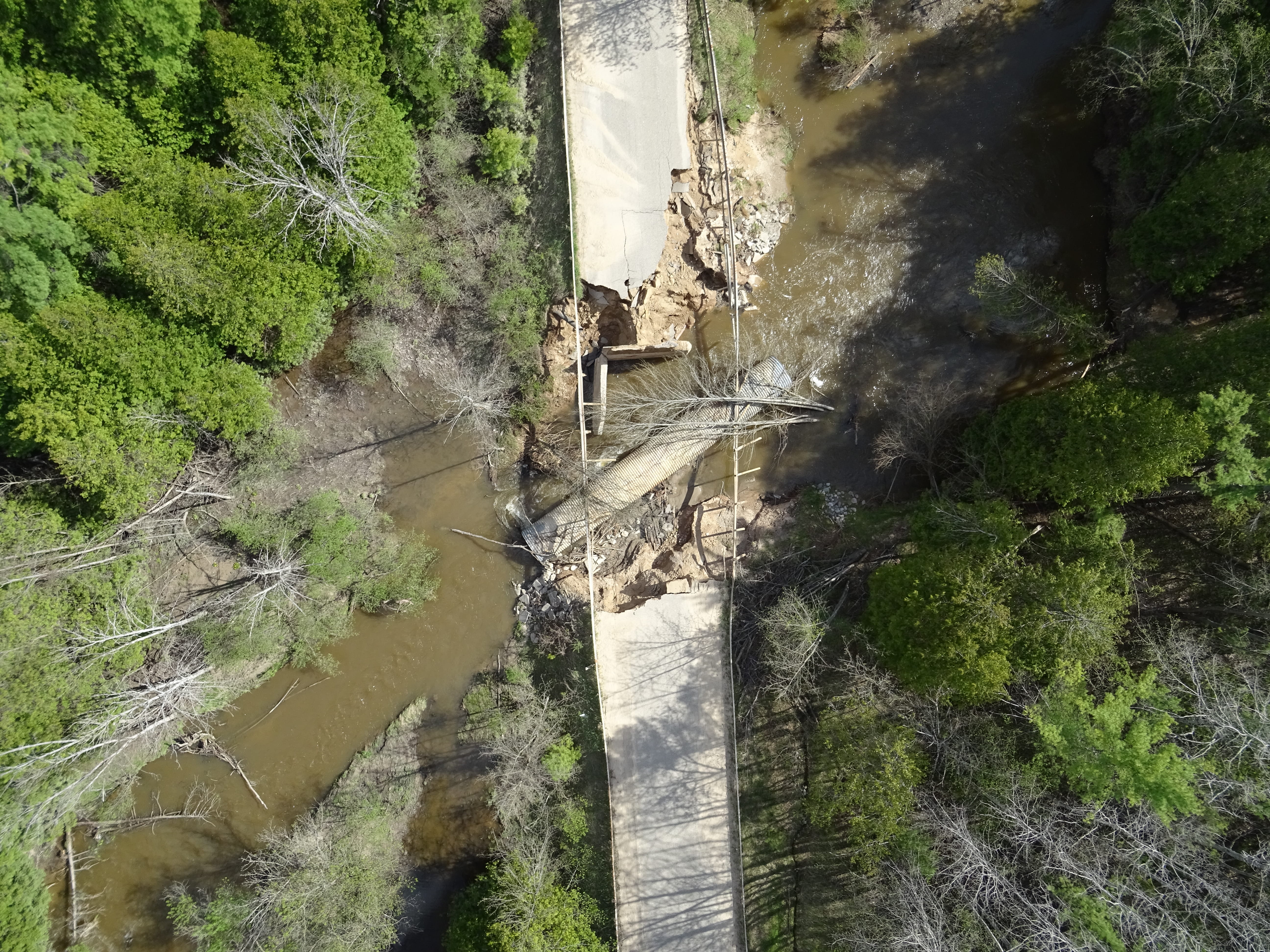 An aerial view of a bridge that has been washed out by flood water. 