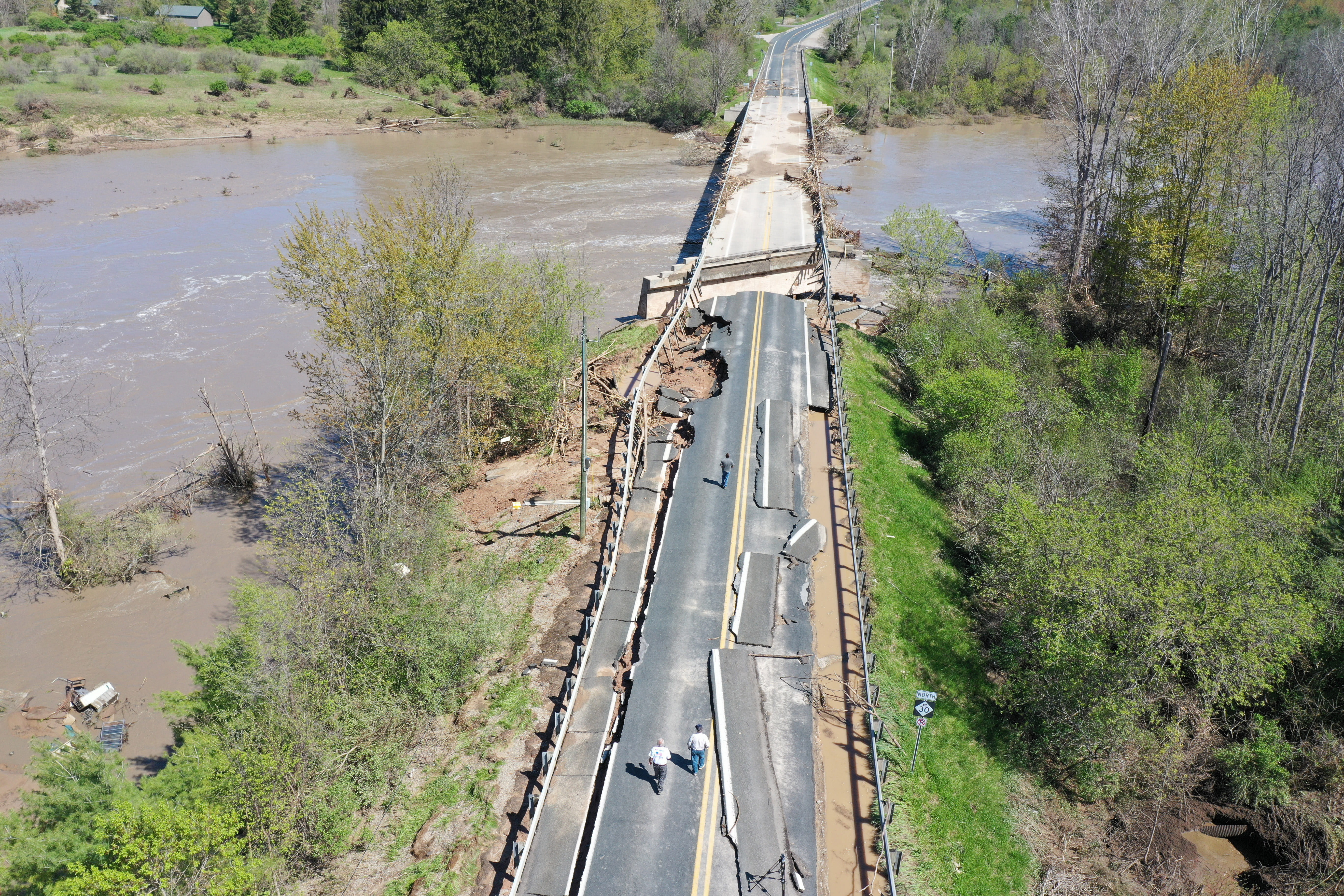A road and a bridge that has been damaged and washed out by flood water. 