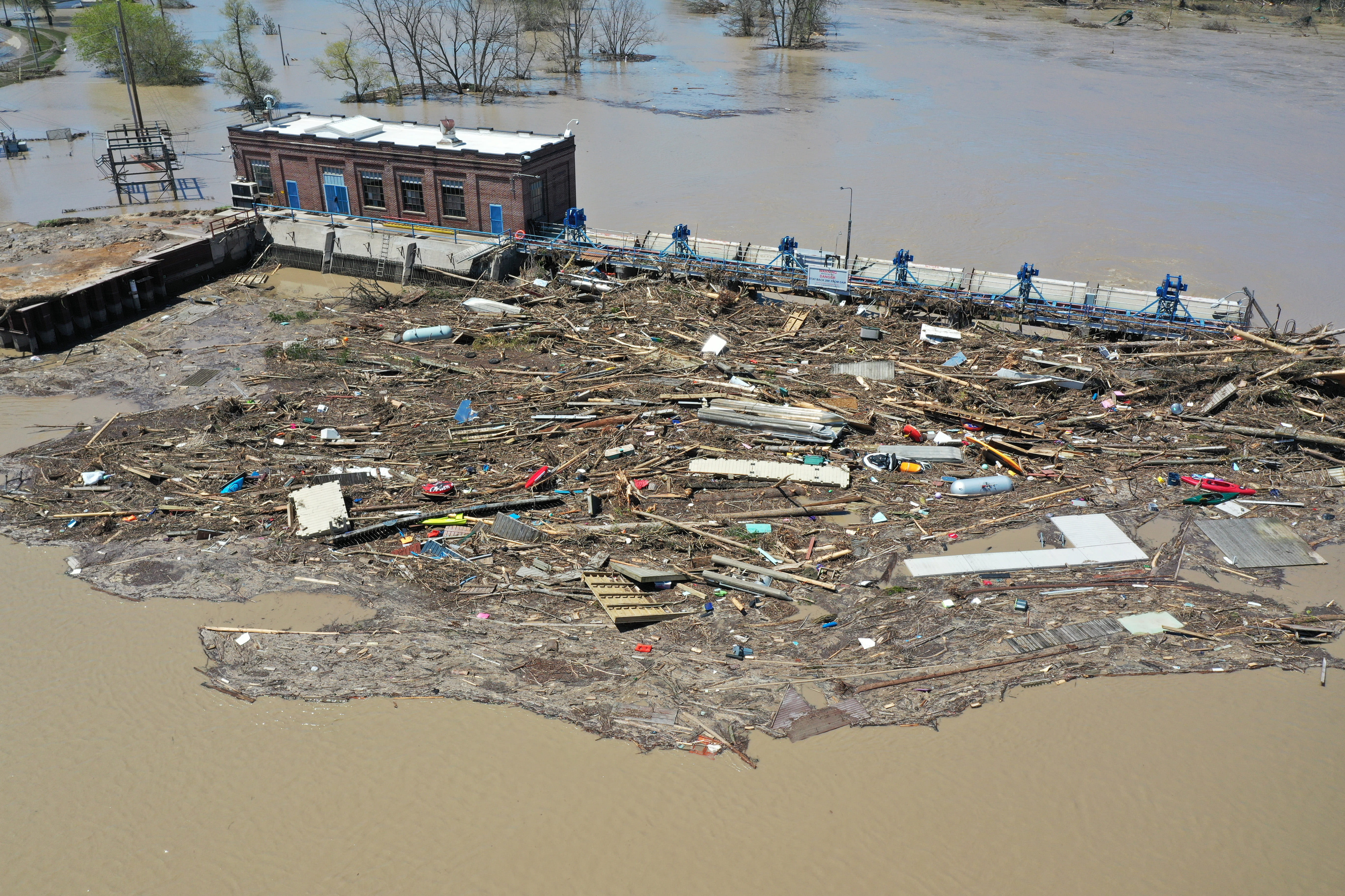 A small building surrounded by flood water and debris. 
