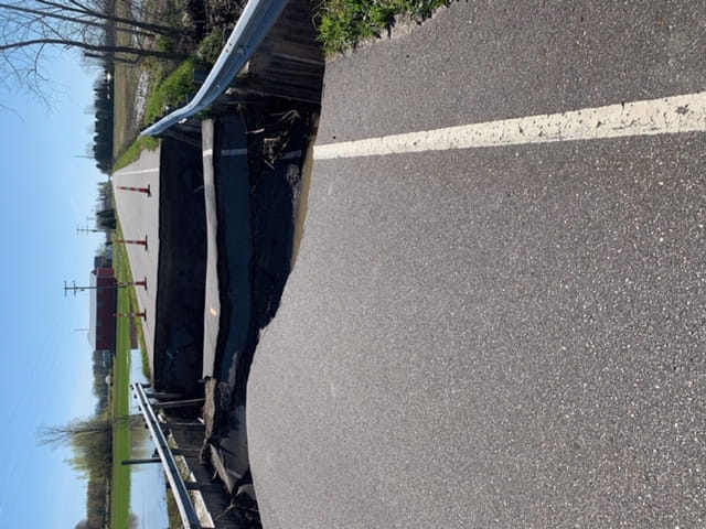 A road and a bridge that have been partially washed out by flooding. 