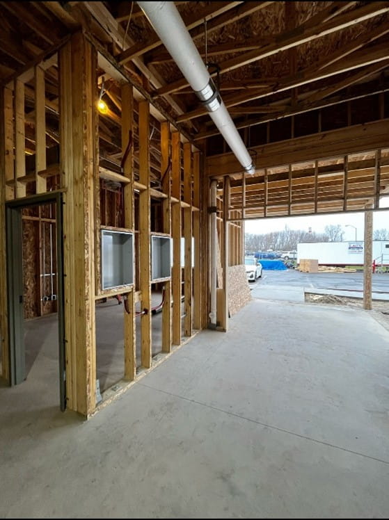 The inside of a building with studs and framing with an opening for a garage door.