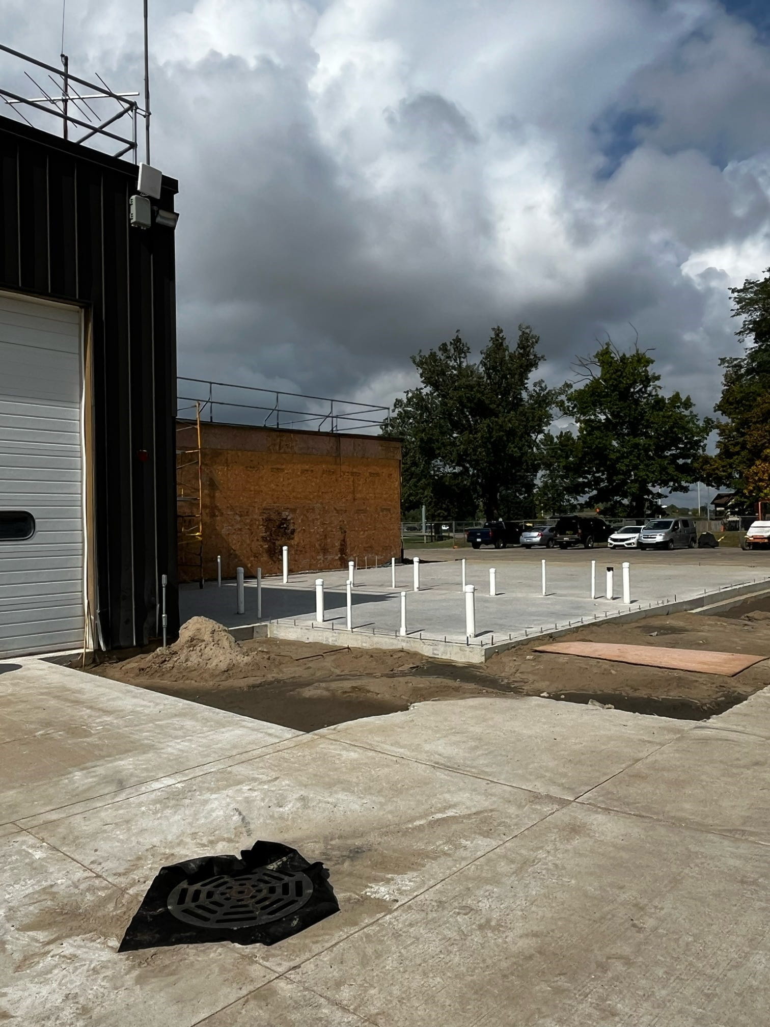 A poured concrete area next to the building with white pipes sticking up.