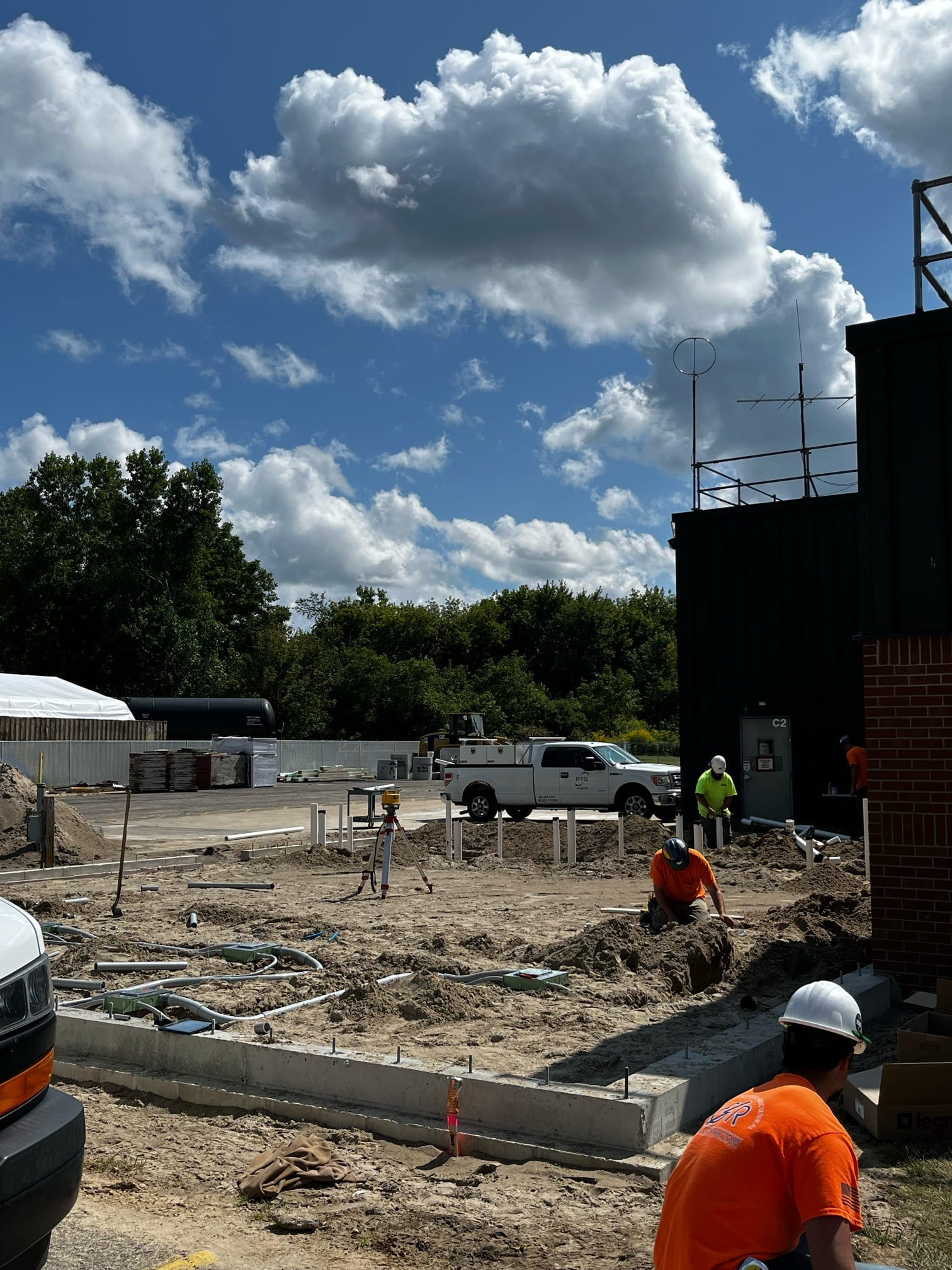 Constructions workers in a dirt area with cinderblock perimeter. 
