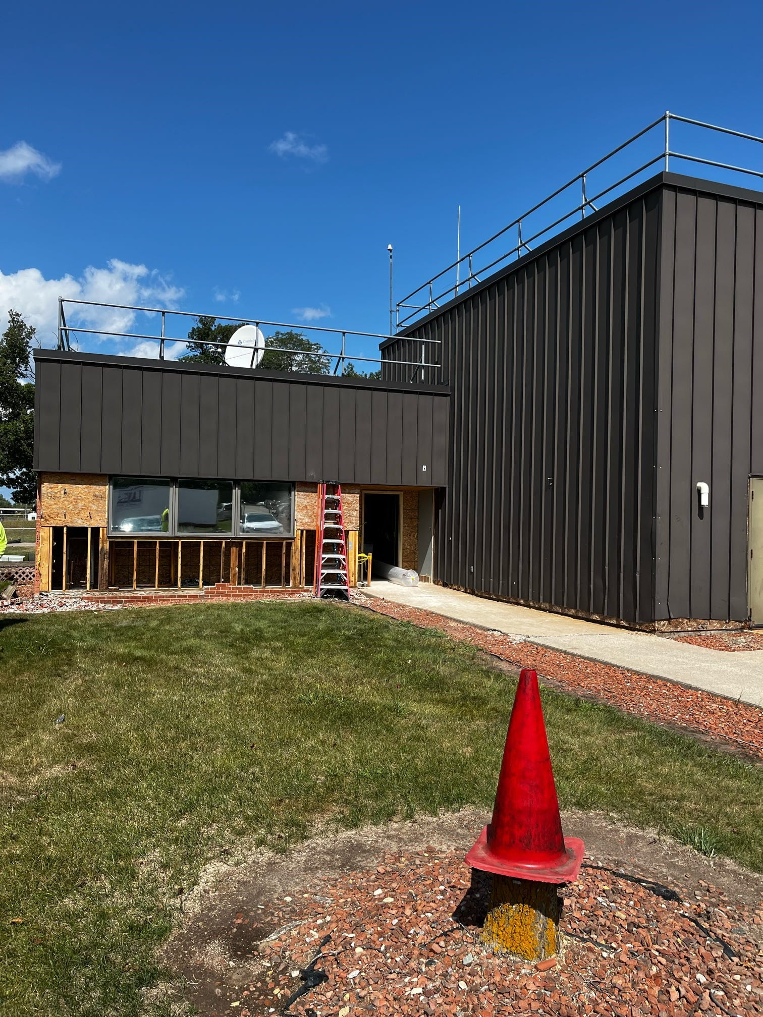 The front of the building with a ladder leaning against it and areas of the wall removed under the windows.