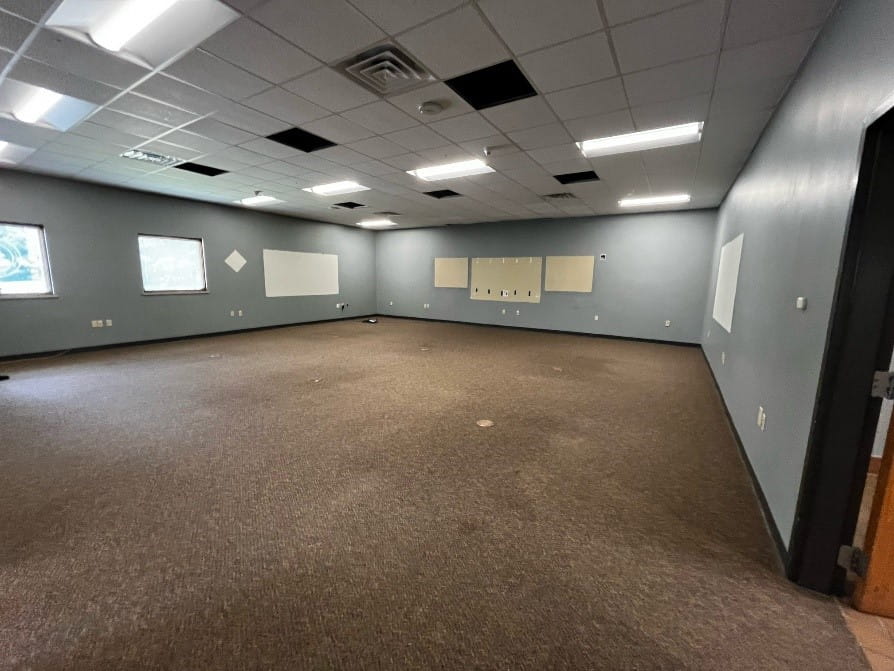 An empty classroom with grey walls and beige carpet.