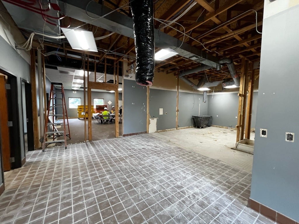 An empty entry way with exposed ceiling, dusty tile floors and exposed wall framing