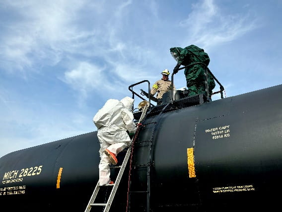 People in hazmat suits climbing onto a tank