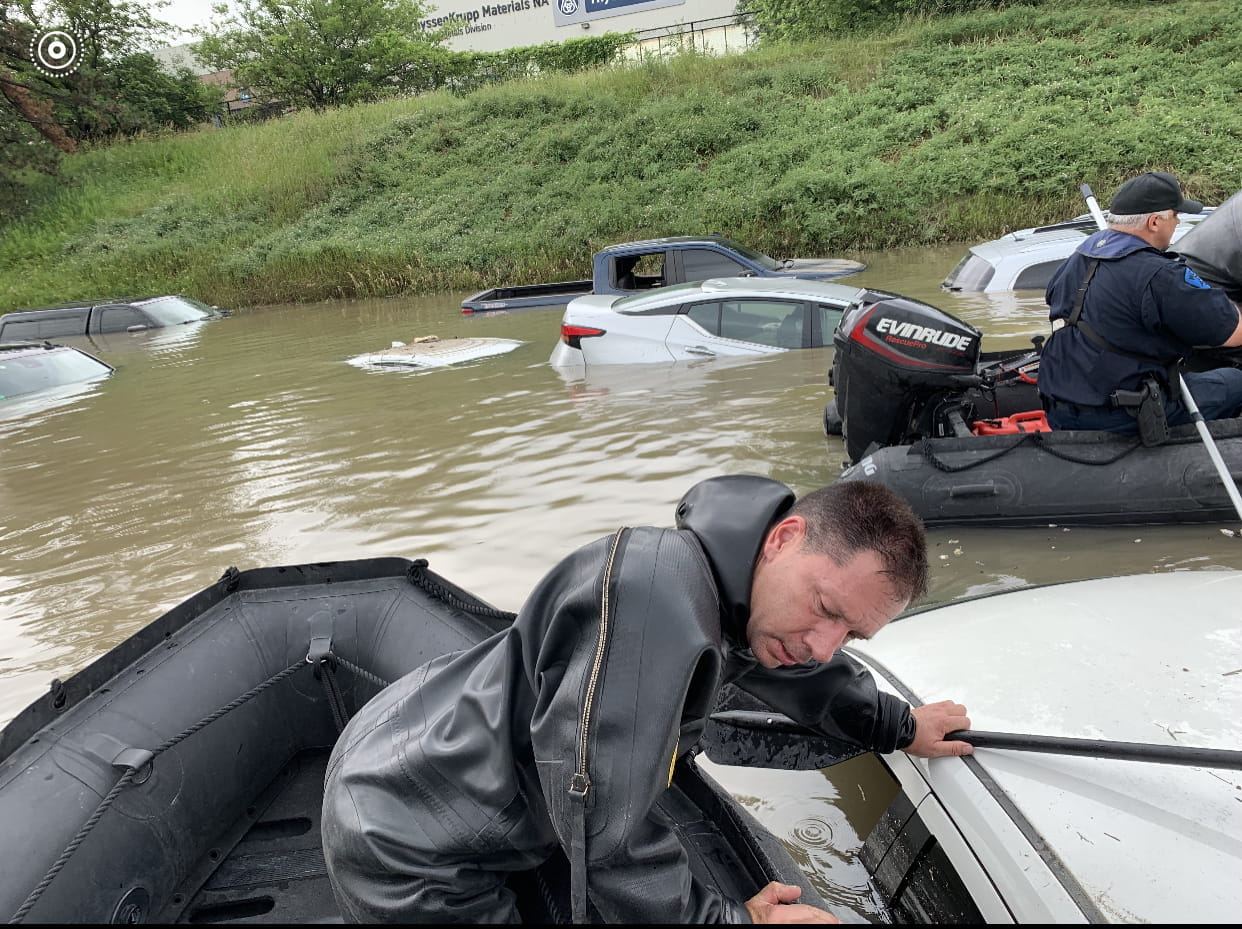 Two MSP Troopers in two small boats checking cars stuck in flood water. 