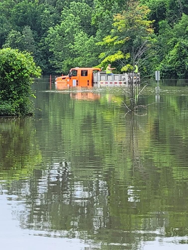 A large truck driving through flood water. 