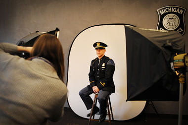 Photographer taking photo of man in trooper uniform and hat in front of white background. 