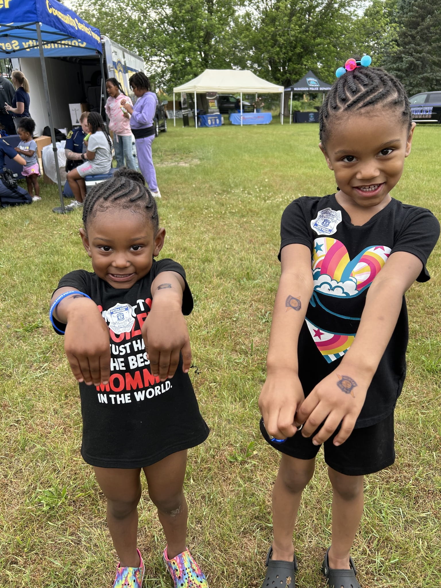 Two children with MSP stickers at outdoor community event. 